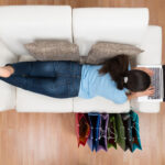High Angle View Of Young Happy Woman On Sofa Shopping Online With Laptop